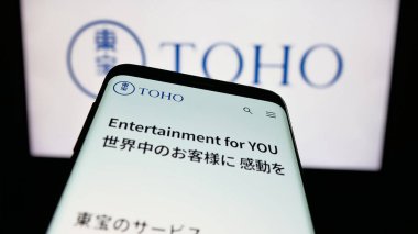 Stuttgart, Almanya - 04-25-2025: Japon eğlence şirketi Toho Co. Ltd. nin internet sayfası ile cep telefonu logonun önünde ekranda. Telefon ekranının sol üst kısmına odaklan.