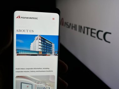 Stuttgart, Almanya - 04-25-2025: Japon ASAHI INTECC Co. Ltd. şirketinin web sitesi ile akıllı telefon sahibi kişi logonun önünde ekranda. Telefon ekranının merkezine odaklan.