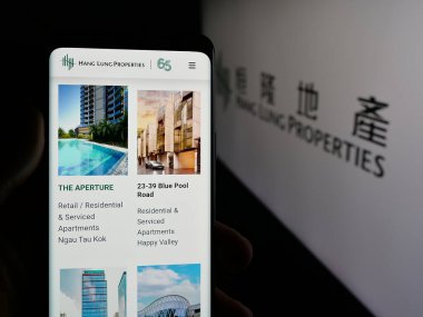 Stuttgart, Almanya - 04-26-2025: Çinli şirket Hang Lung Properties Limited 'in web sayfası olan cep telefonu logosu önünde ekranda. Telefon ekranının merkezine odaklan.