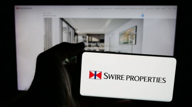 Stuttgart, Almanya - 04-26-2025: Emlak şirketi Swire Properties Limited 'in logosuna sahip cep telefonu sahibi kişi web sitesinin önünde ekranda. Telefon ekranına odaklan.
