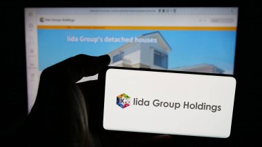 Stuttgart, Almanya - 04-26-2025: Japon Iida Group Holding Co. Ltd. şirketinin logosunun bulunduğu cep telefonu web sayfası önünde ekranda. Telefon ekranına odaklan.