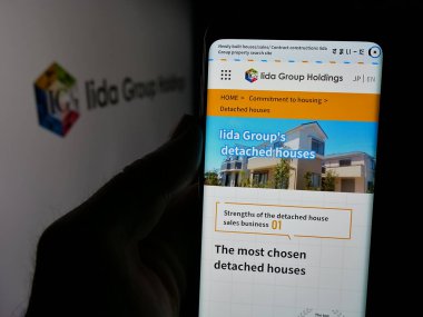 Stuttgart, Almanya - 04-26-2025: Japon Iida Group Holding Co. Ltd. şirketinin web sitesi ile akıllı telefon sahibi kişi logonun önünde ekranda. Telefon ekranının merkezine odaklan.