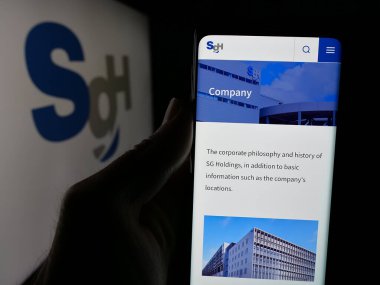 Stuttgart, Almanya - 04-26-2025: Lojistik şirketi SG Holding Co. Ltd. nin web sitesi ile akıllı telefon sahibi kişi logonun önünde ekranda. Telefon ekranının merkezine odaklan.