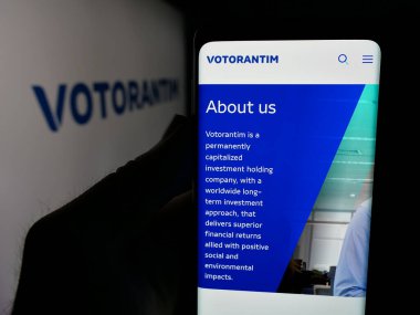 Stuttgart, Almanya - 04-26-2025: Brezilyalı yatırım şirketi Votorantim S.A. 'nın web sitesi ile akıllı telefonu olan kişi logonun önünde ekranda. Telefon ekranının merkezine odaklan.