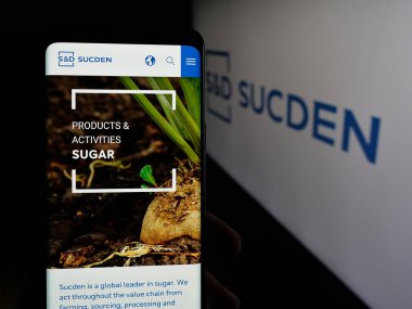 Stuttgart, Almanya - 04-26-2025: Fransız şirketi Sucres et Denrees 'in (Sucden) web sitesi ile akıllı telefonu olan kişi logonun önünde ekranda. Telefon ekranının merkezine odaklan.