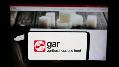 Stuttgart, Almanya - 04-26-2025: Web sayfası önünde üzerinde palmiye yağı şirketi Golden Agri-Resources (GAR) logosu bulunan cep telefonu sahibi kişi. Telefon ekranına odaklan.