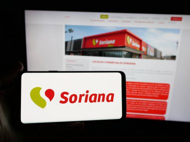 Stuttgart, Almanya - 04-26-2025: Şirket organizasyonu Soriana S.A.B. logosuna sahip akıllı telefon sahibi kişi de C.V. web sitesinin önünde ekranda. Telefon ekranına odaklan.