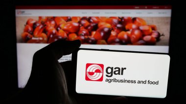 Stuttgart, Almanya - 04-26-2025: Web sayfası önünde üzerinde palmiye yağı şirketi Golden Agri-Resources (GAR) logosu bulunan cep telefonu sahibi kişi. Telefon ekranına odaklan.