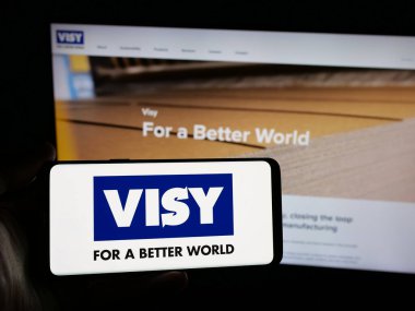 Stuttgart, Almanya - 04-26-2025: İnternet sitesinin önünde ambalaj şirketi Visy Industries 'in logosuna sahip akıllı telefon sahibi kişi. Telefon ekranına odaklan.