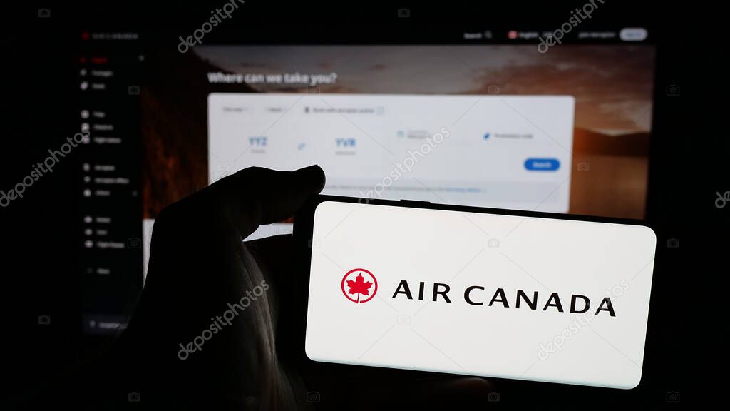 Stuttgart, Germany - 04-25-2025: Person holding mobile phone with logo of Canadian airline company Air Canada on screen in front of web page. Focus on phone display.