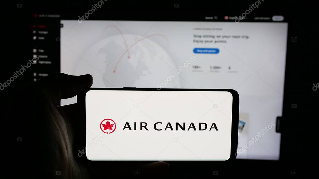 Stuttgart, Germany - 04-25-2025: Person holding cellphone with logo of Canadian airline company Air Canada on screen in front of webpage. Focus on phone display.