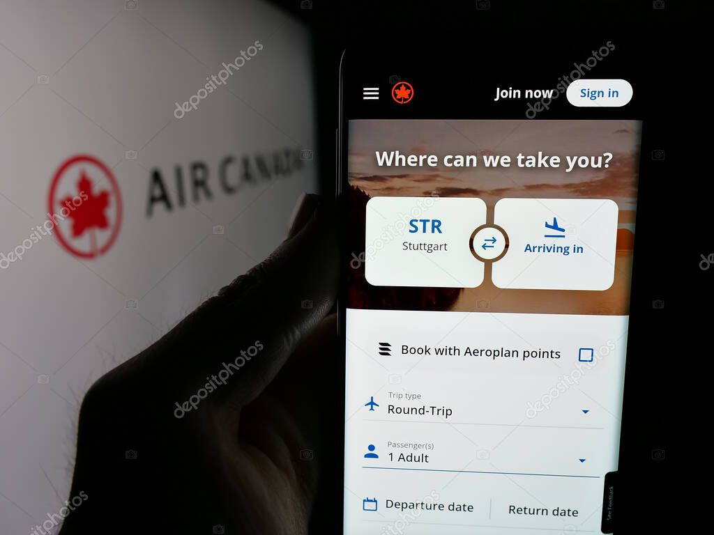 Stuttgart, Germany - 04-25-2025: Person holding smartphone with website of Canadian airline company Air Canada on screen in front of logo. Focus on center of phone display.