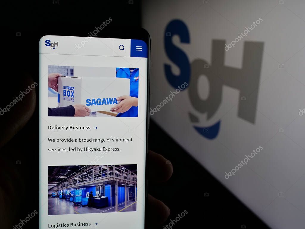 Stuttgart, Germany - 04-26-2025: Person holding cellphone with web page of logistics company SG Holdings Co. Ltd. on screen in front of logo. Focus on center of phone display.
