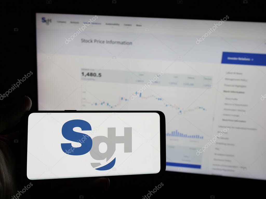 Stuttgart, Germany - 04-26-2025: Person holding smartphone with logo of logistics company SG Holdings Co. Ltd. on screen in front of website. Focus on phone display.