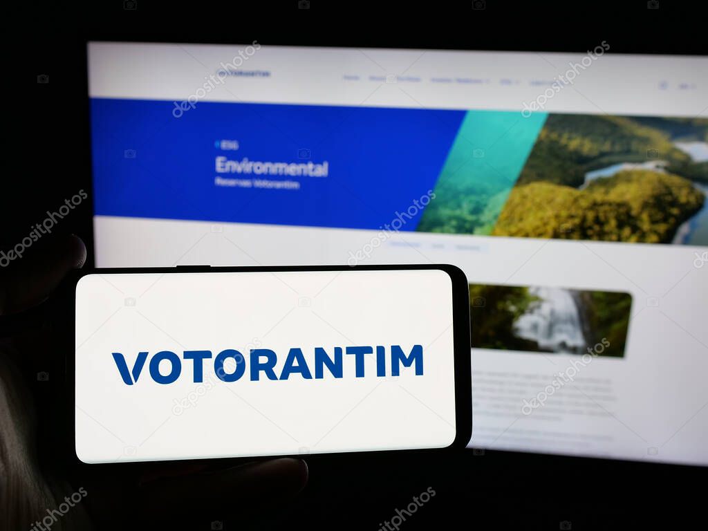 Stuttgart, Germany - 04-26-2025: Person holding smartphone with logo of Brazilian investment company Votorantim S.A. on screen in front of website. Focus on phone display.