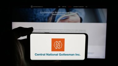 Stuttgart, Almanya - 04-28-2025: İnternet sayfası önünde Central National-Gottesman Inc. (CNG) şirketinin logosunun bulunduğu cep telefonu sahibi kişi. Telefon ekranına odaklan.