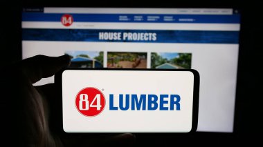 Stuttgart, Almanya - 05-02-2025: İnternet sayfası önünde üzerinde ABD 'li 84 Kereste Şirketi (84Lumber) logosu bulunan cep telefonu sahibi kişi. Telefon ekranına odaklan.