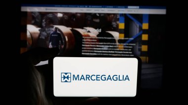 Stuttgart, Almanya - 05-02-2025: İtalyan çelik şirketi Marcegaglia S.P.A. 'nın logosunu elinde tutan kişi web sayfasının önünde ekranda. Telefon ekranına odaklan.