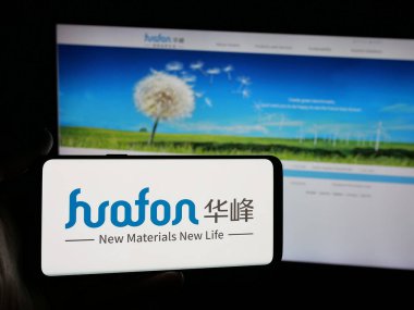 Stuttgart, Almanya - 05-02-2025: Çinli kimya şirketi Huafon Group 'un logosunu elinde tutan kişi web sitesinin önünde ekranda. Telefon ekranına odaklan.