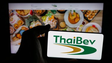 Stuttgart, Almanya - 05-02-2025: İnternet sayfası önünde ekranda Thai Beverage plc (ThaiBev) şirketinin logosuna sahip cep telefonu sahibi kişi. Telefon ekranına odaklan.