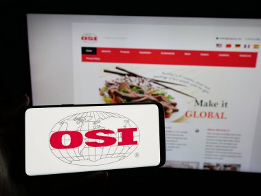 Stuttgart, Almanya - 05-02-2025: ABD 'li et işleme şirketi OSI Group LLC' nin logosuna sahip akıllı telefon sahibi kişi web sitesinin önünde ekranda. Telefon ekranına odaklan.
