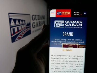 Stuttgart, Almanya - 05-02-2025: Endonezyalı tütün şirketi Gudang Garam 'ın web sitesi ile cep telefonu tutan kişi logonun önünde ekranda. Telefon ekranının merkezine odaklan.
