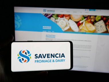 Stuttgart, Almanya - 05-03-2025: Fransız mandıra şirketi Savencia S.A. 'nın logosunu elinde tutan kişi web sitesinin önünde ekranda. Telefon ekranına odaklan.