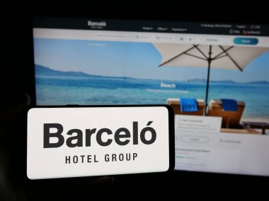 Stuttgart, Almanya - 05-03-2025: İspanyol konukseverlik şirketi Grupo Barcelo 'nun logosunun bulunduğu akıllı telefonu web sitesinin önünde elinde tutan kişi. Telefon ekranına odaklan.