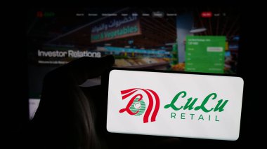 Stuttgart, Almanya - 05-03-2025: Web sayfasının önünde ekranda Lulu Perakende Holding 'in logosuna sahip cep telefonu sahibi kişi. Telefon ekranına odaklan.