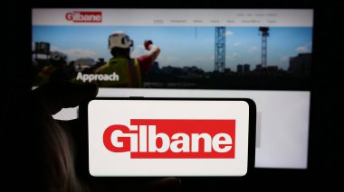 Stuttgart, Almanya - 05-03-2025: ABD 'li inşaat şirketi Gilbane Inc.' in logosunun bulunduğu cep telefonu web sayfasının önünde ekranda. Telefon ekranına odaklan.
