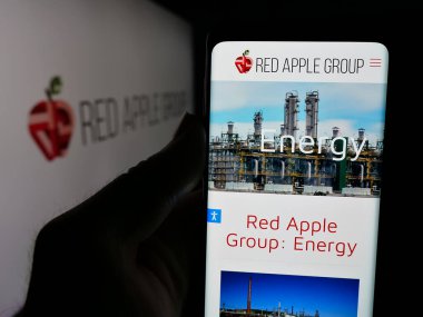 Stuttgart, Almanya - 05-03-2025: ABD 'li emlak şirketi Red Apple Group Inc.' in web sayfası ile cep telefonu tutan kişi logonun önünde ekranda. Telefon ekranının merkezine odaklan.