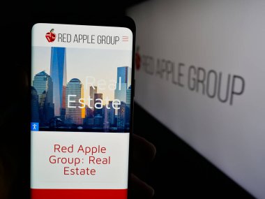 Stuttgart, Almanya - 05-03-2025: ABD 'li emlak şirketi Red Apple Group Inc.' in web sitesi ile akıllı telefon sahibi kişi logonun önünde ekranda. Telefon ekranının merkezine odaklan.