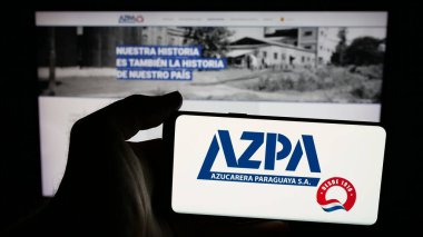 Stuttgart, Almanya - 05-03-2025: Web sayfasının önünde Azucarera Paraguaya S.A. (AZPA) şirketinin logosuna sahip cep telefonu sahibi kişi. Telefon ekranına odaklan.