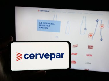 Stuttgart, Almanya - 05-03-2025: İnternet sitesinin önünde Cerveceria Paraguaya S.A. (Cervepar) şirketinin logosuna sahip akıllı telefonu elinde tutan kişi. Telefon ekranına odaklan.