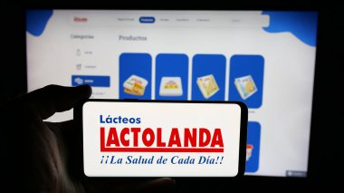 Stuttgart, Almanya - 05-04-2025: Paraguay mandıra şirketi Lactolanda 'nın logosuyla cep telefonu tutan kişi web sitesinin önünde ekranda. Telefon ekranına odaklan.