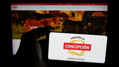 Stuttgart, Almanya - 05-04-2025: İnternet sayfasının önünde üzerinde et şirketi Frigorifico Concepcion S.A. logosu bulunan cep telefonu sahibi kişi. Telefon ekranına odaklan.