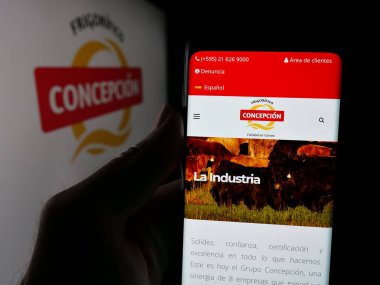 Stuttgart, Almanya - 05-04-2025: Et şirketi Frigorifico Concepcion S.A. 'nın web sitesi ile akıllı telefonu olan kişi logo önünde ekranda. Telefon ekranının merkezine odaklan.
