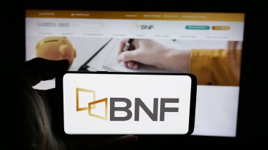 Stuttgart, Almanya - 05-04-2025: İnternet sayfası önünde Banco Nacional de Fomento (BNF) şirketinin logosunun bulunduğu cep telefonu sahibi kişi. Telefon ekranına odaklan.