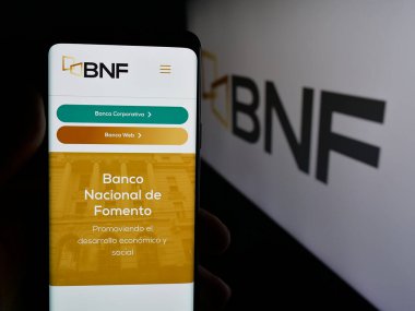 Stuttgart, Almanya - 05-04-2025: Logo önündeki ekranda Banco Nacional de Fomento (BNF) şirketinin web sayfası bulunan kişi. Telefon ekranının merkezine odaklan.