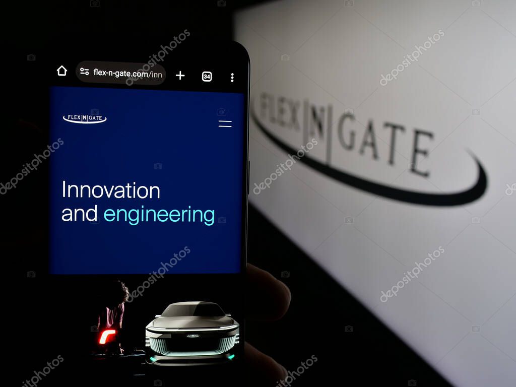 Stuttgart, Germany - 05-02-2025: Person holding smartphone with website of US automotive company Flex-N-Gate LLC on screen in front of logo. Focus on center of phone display.