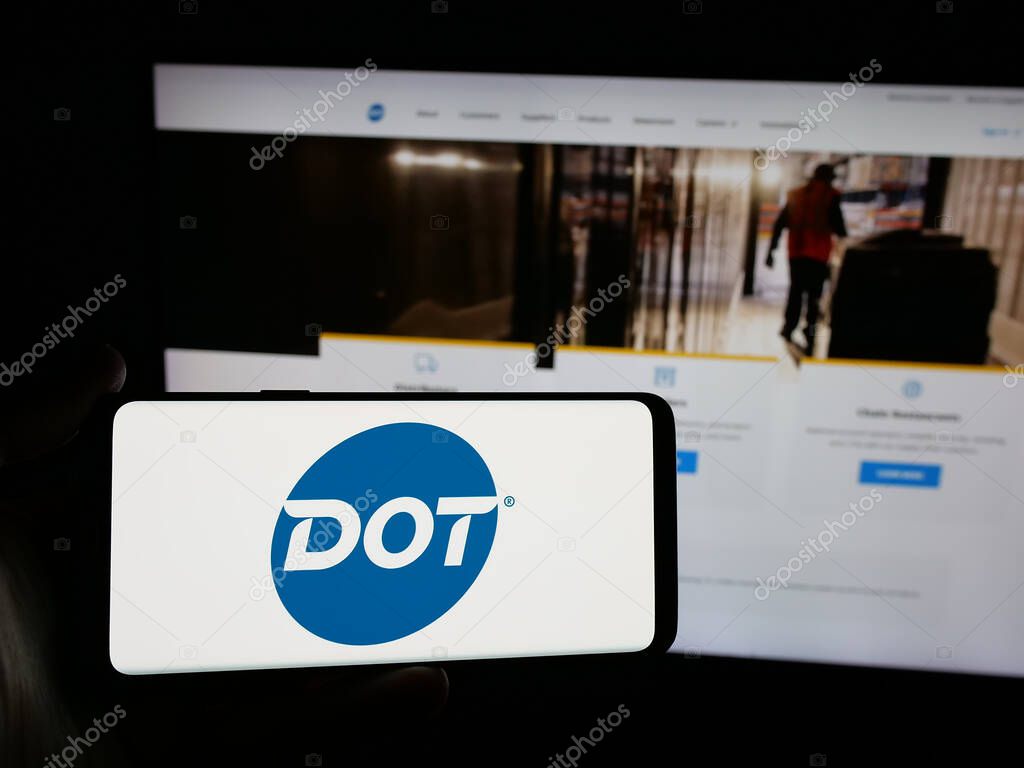 Stuttgart, Germany - 05-02-2025: Person holding smartphone with logo of US foodservice company Dot Foods Inc. on screen in front of website. Focus on phone display.