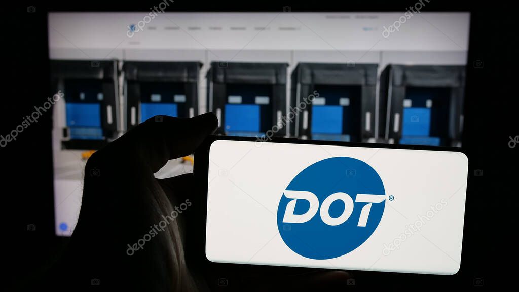 Stuttgart, Germany - 05-02-2025: Person holding mobile phone with logo of US foodservice company Dot Foods Inc. on screen in front of web page. Focus on phone display.