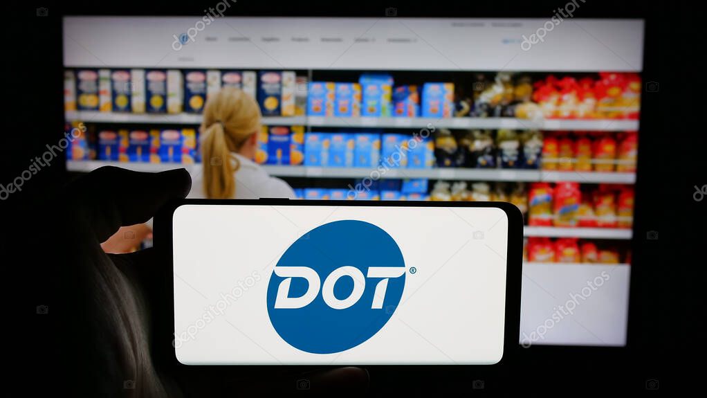 Stuttgart, Germany - 05-02-2025: Person holding cellphone with logo of US foodservice company Dot Foods Inc. on screen in front of webpage. Focus on phone display.