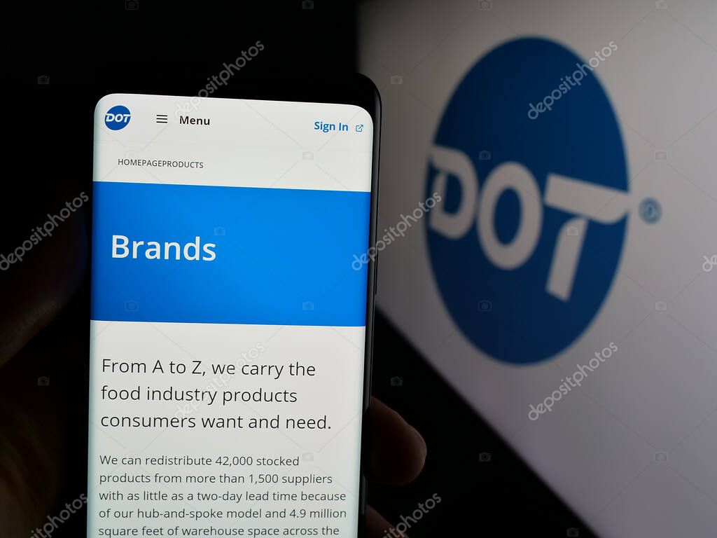 Stuttgart, Germany - 05-02-2025: Person holding smartphone with website of US foodservice company Dot Foods Inc. on screen in front of logo. Focus on center of phone display.