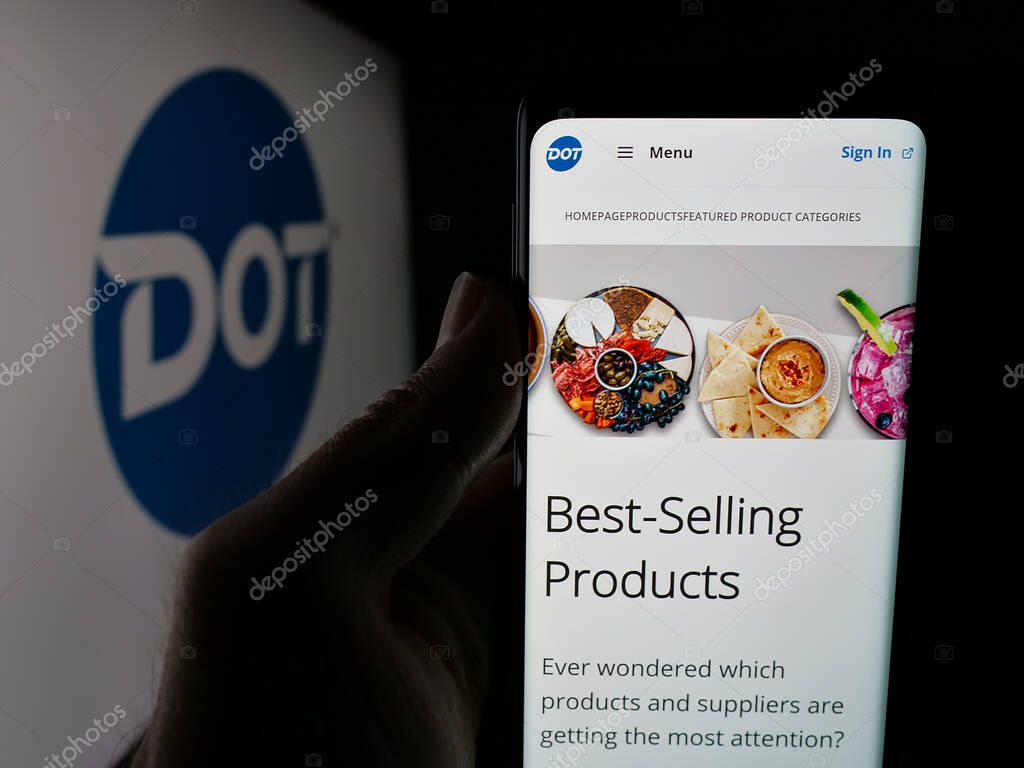 Stuttgart, Germany - 05-02-2025: Person holding cellphone with web page of US foodservice company Dot Foods Inc. on screen in front of logo. Focus on center of phone display.