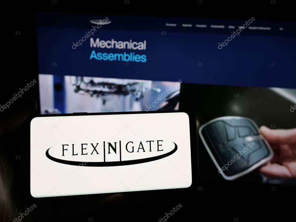 Stuttgart, Germany - 05-02-2025: Person holding smartphone with logo of US automotive company Flex-N-Gate LLC on screen in front of website. Focus on phone display.