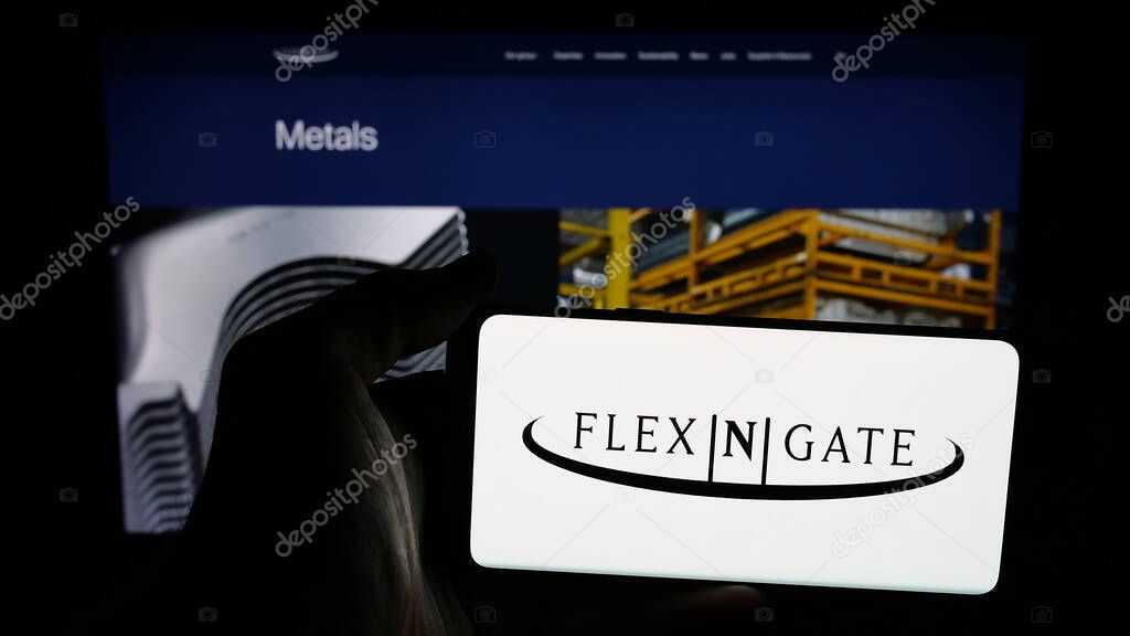 Stuttgart, Germany - 05-02-2025: Person holding mobile phone with logo of US automotive company Flex-N-Gate LLC on screen in front of web page. Focus on phone display.