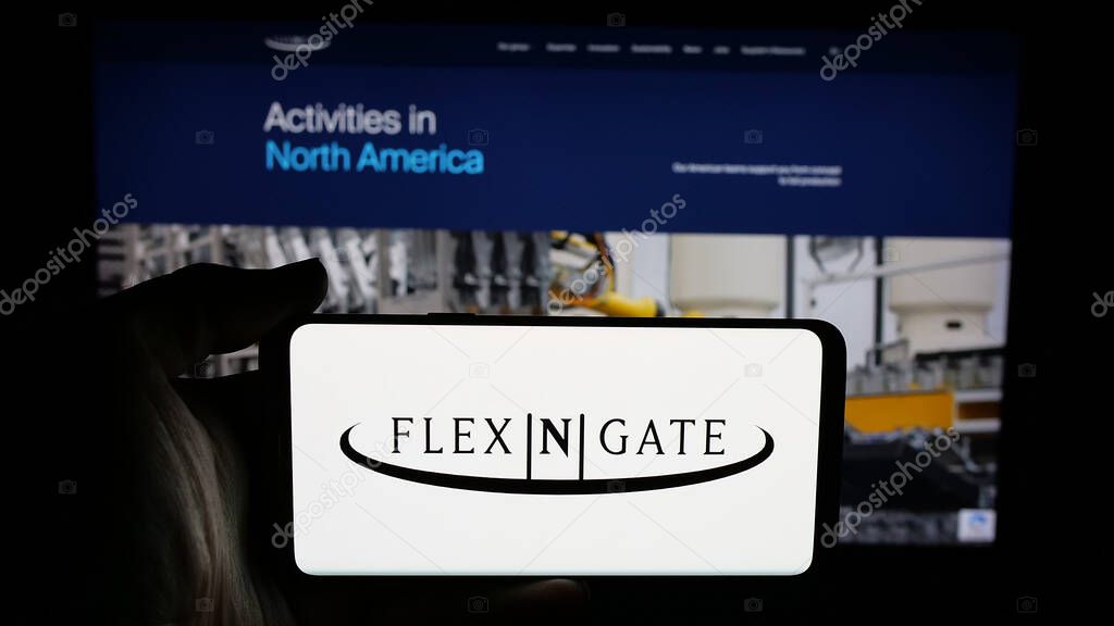 Stuttgart, Germany - 05-02-2025: Person holding cellphone with logo of US automotive company Flex-N-Gate LLC on screen in front of webpage. Focus on phone display.