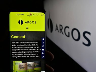 Stuttgart, Almanya - 05-04-2025: Logo önünde ekranda Grupo Argos S.A. adlı inşaat malzemeleri şirketinin web sitesiyle akıllı telefon tutan kişi. Telefon ekranının merkezine odaklan.