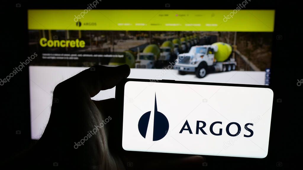 Stuttgart, Germany - 05-04-2025: Person holding mobile phone with logo of building materials company Grupo Argos S.A. on screen in front of web page. Focus on phone display.